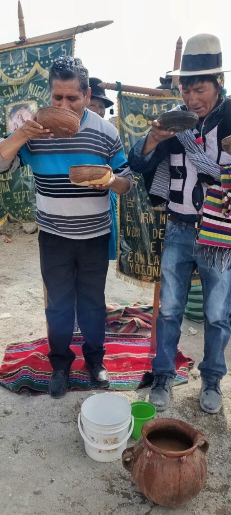 Die Kernbestandteile des Brauchs

​1. Das Trankopfer an Pachamama Ch'allar

Das Getränk: In dem großen Tontopf (Cántaro) am Boden befindet sich Chicha, ein traditionell aus Keimmais vergorenes Getränk des Andenraums.

Die Gefäße: Getrunken wird aus Holz- oder Kürbisschalen, den sogenannten Tutumas.

Das Ritual: Bevor getrunken wird, vergießt man üblicherweise einige Tropfen der Chicha auf die Erde (oder den Boden). Dies ist die eigentliche Ch'alla – ein Dankes- und Bitte-Opfer an Pachamama (Mutter Erde) für Fruchtbarkeit, Schutz und Gesundheit.
